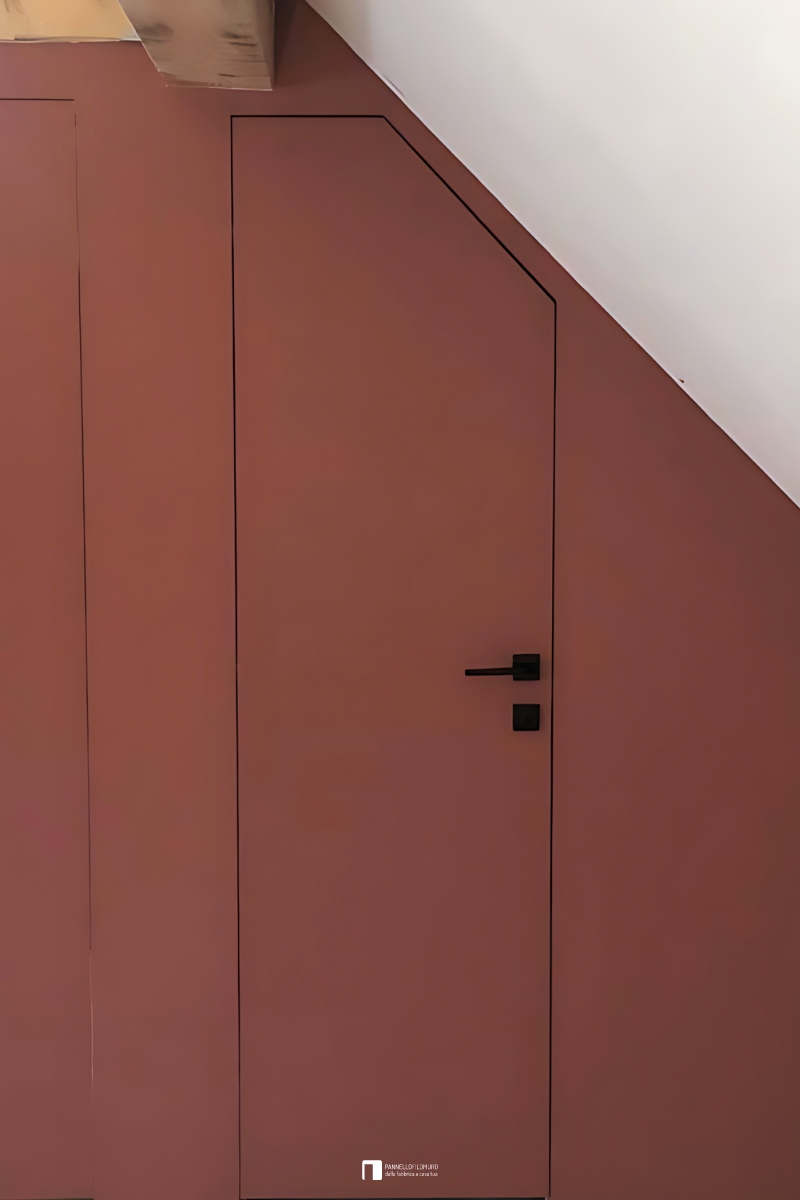 Porta battente filomuro con traversi inclinati per mansarda. L'anta è dipinta come la parete per il massimo effetto a scomparsa