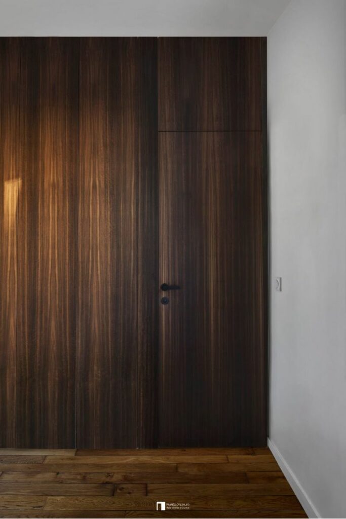 Porta battente filomuro con maniglia a cura del cliente e in finitura essenza di legno come la parete adiacente