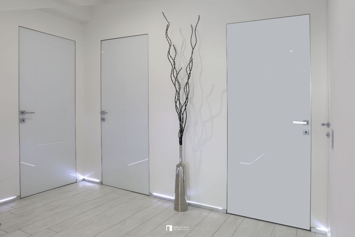 Porte battenti filomuro a confronto con maniglia quadra e finitura in vetro bianco